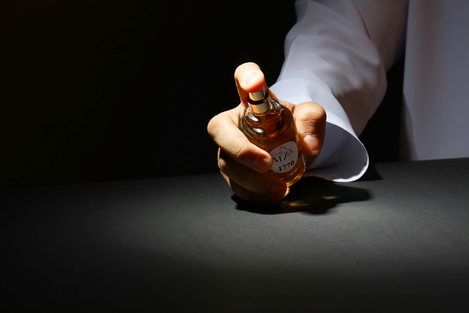 Orientalne perfumy damskie i męskie na co dzień i na wieczór – przewodnik po wyjątkowych zapachach Dłoń trzymająca elegancki flakon perfum na ciemnym tle
