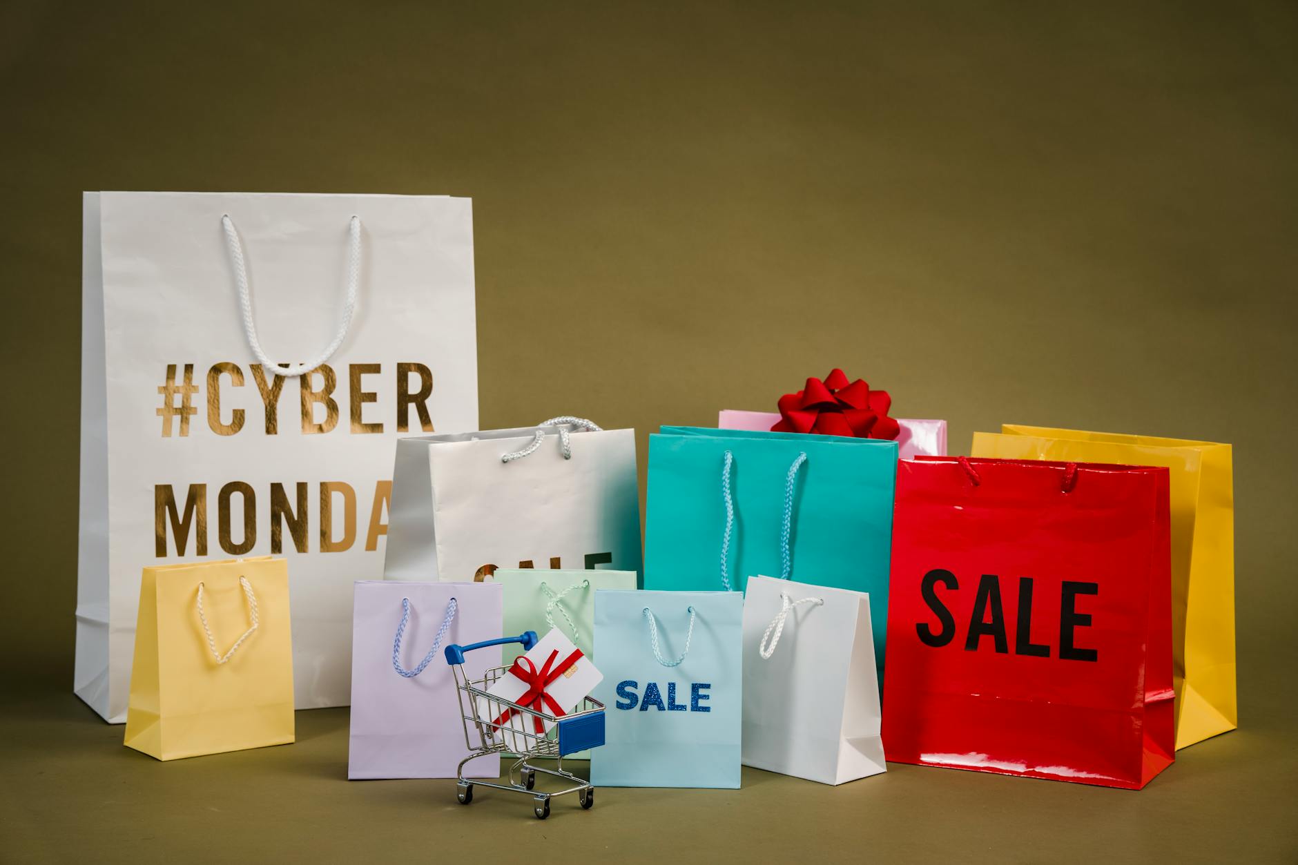 Kolorowe torby zakupowe z napisem Cyber Monday i mały wózek z prezentami