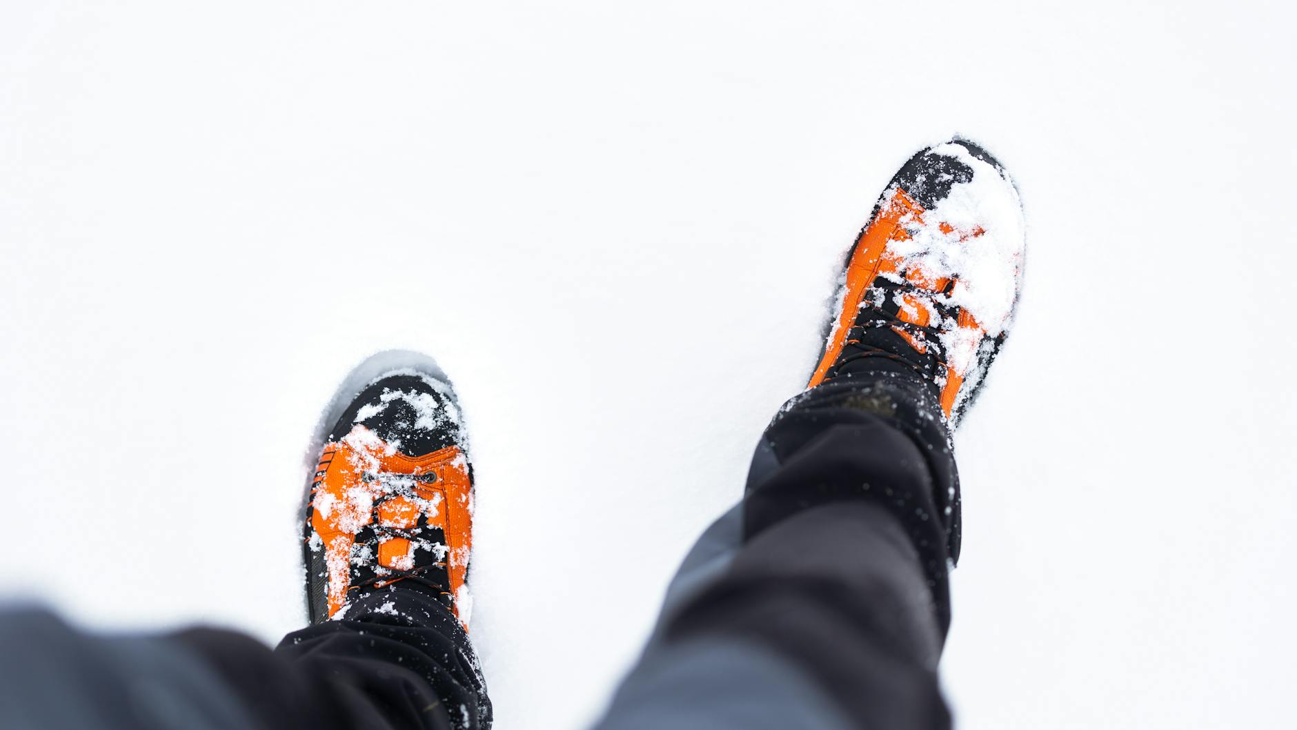 Pomarańczowe buty zimowe z góry, obsypane śniegiem