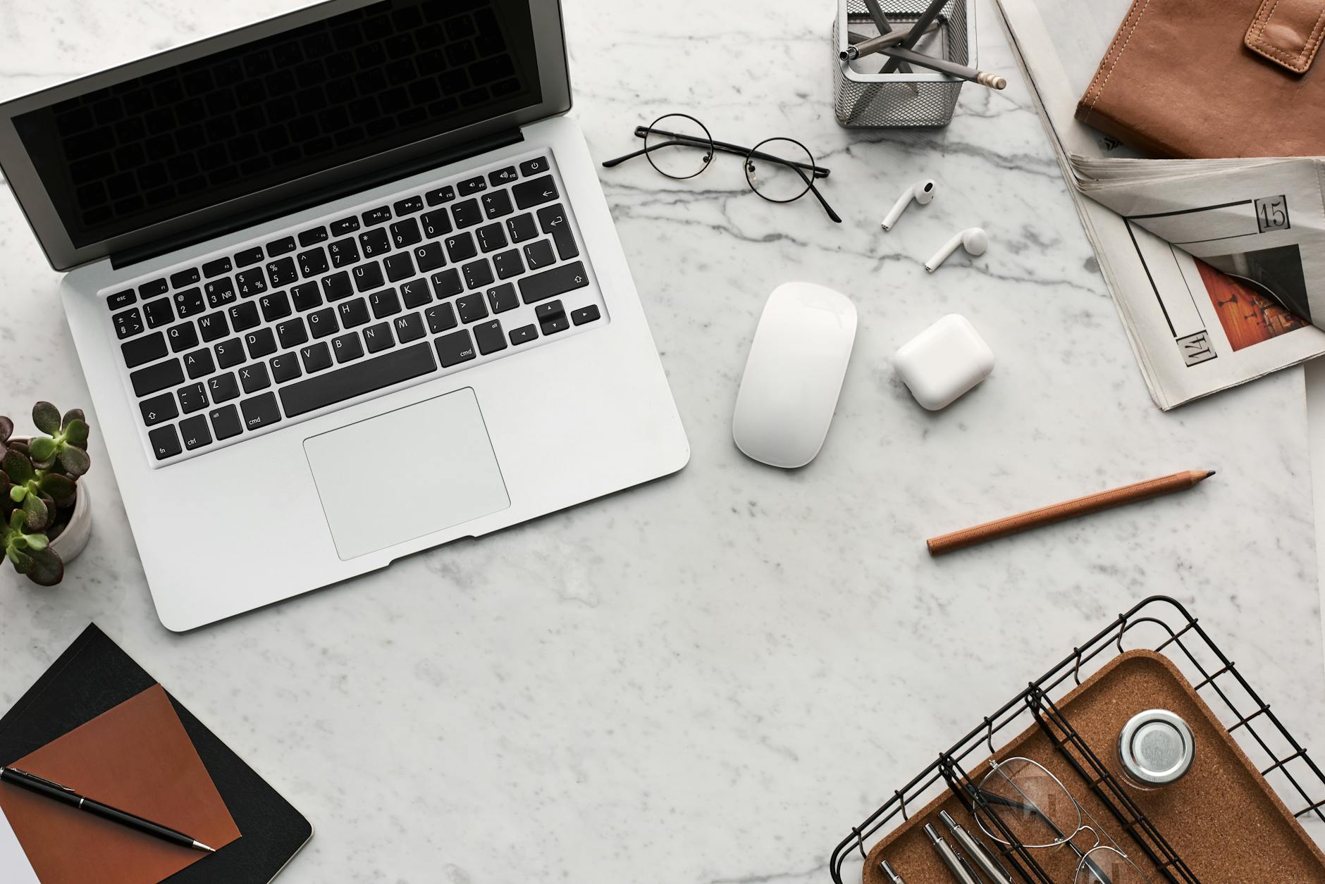Minimalistyczne biurko z laptopem, słuchawkami AirPods i przyborami