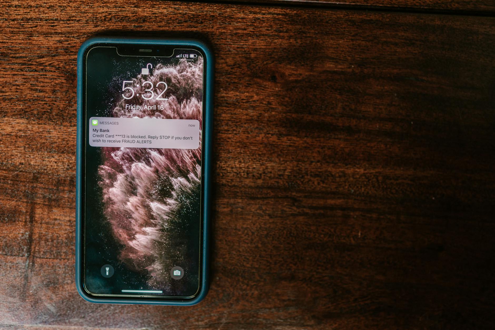 Smartfon na drewnianym stole z powiadomieniem o alercie bankowym