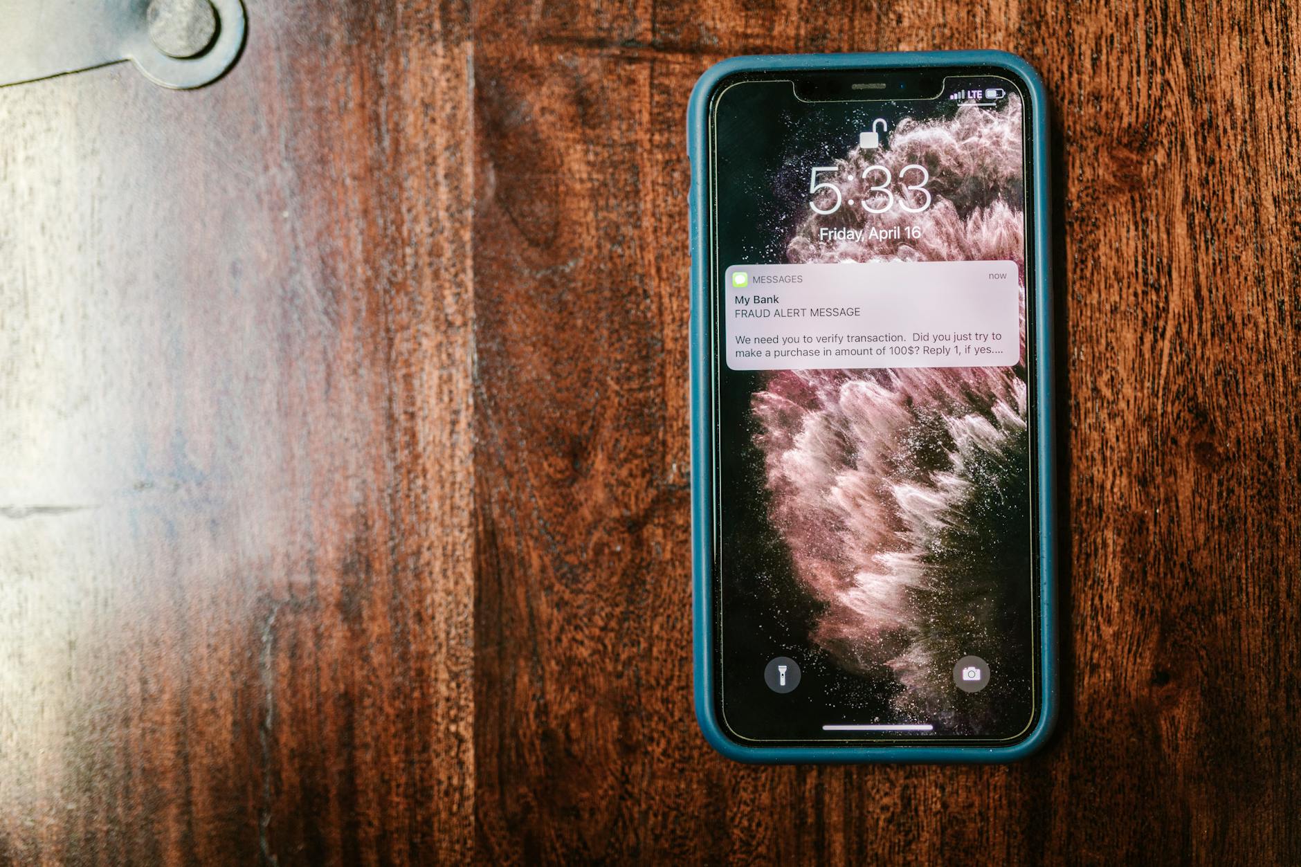 Smartfon na stole z wyświetlonym komunikatem o podejrzeniu oszustwa
