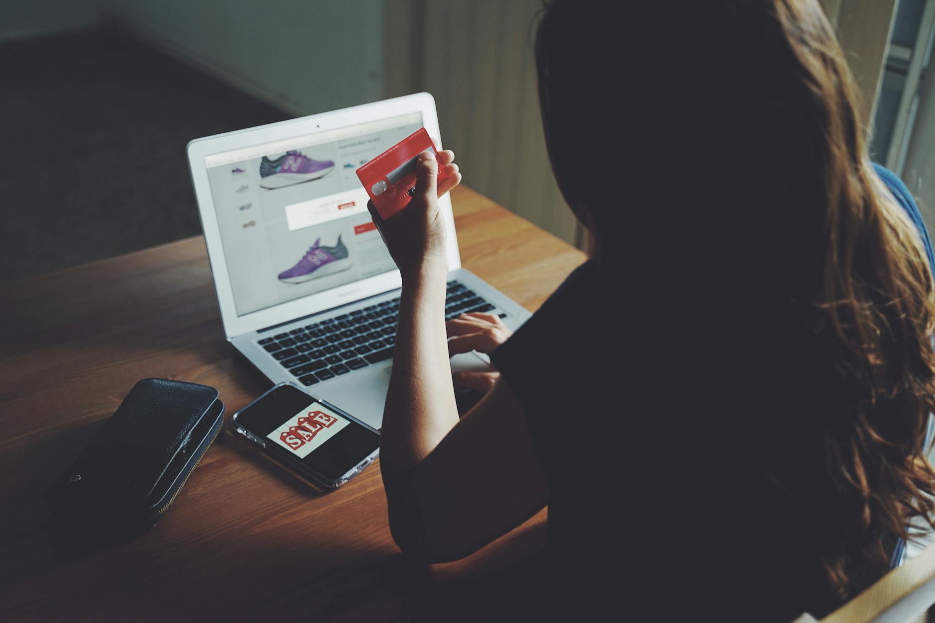Kobieta kupuje online na laptopie, trzymając kartę płatniczą