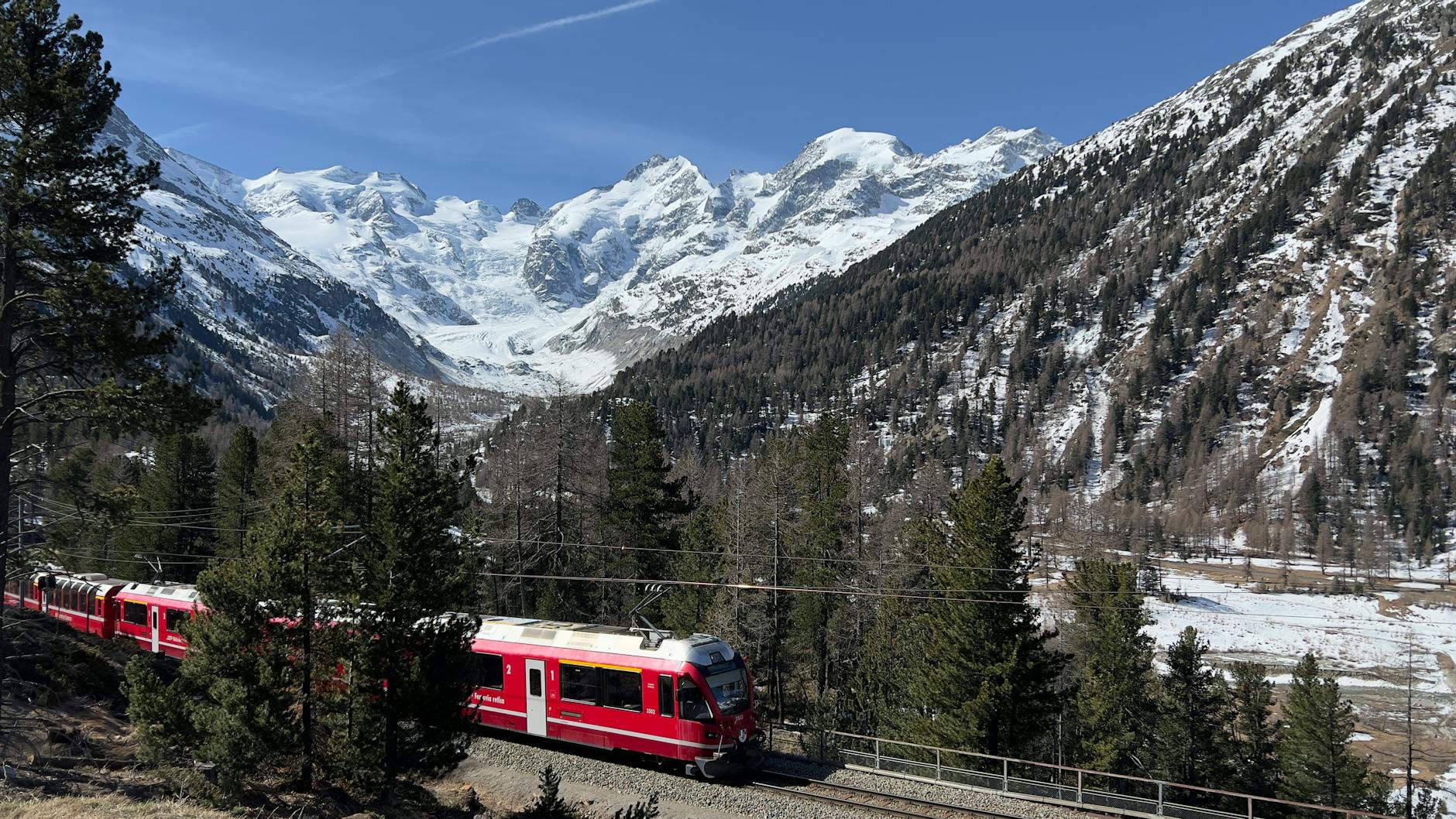 Czerwony pociąg Bernina Express jedzie przez ośnieżone Alpy Szwajcarskie