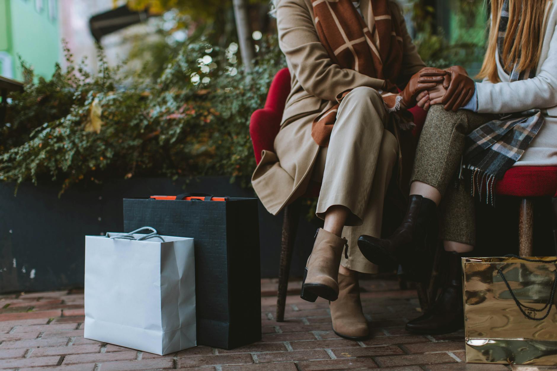 Dwie kobiety jesienią na zewnątrz z torbami i sztybletami z outletu