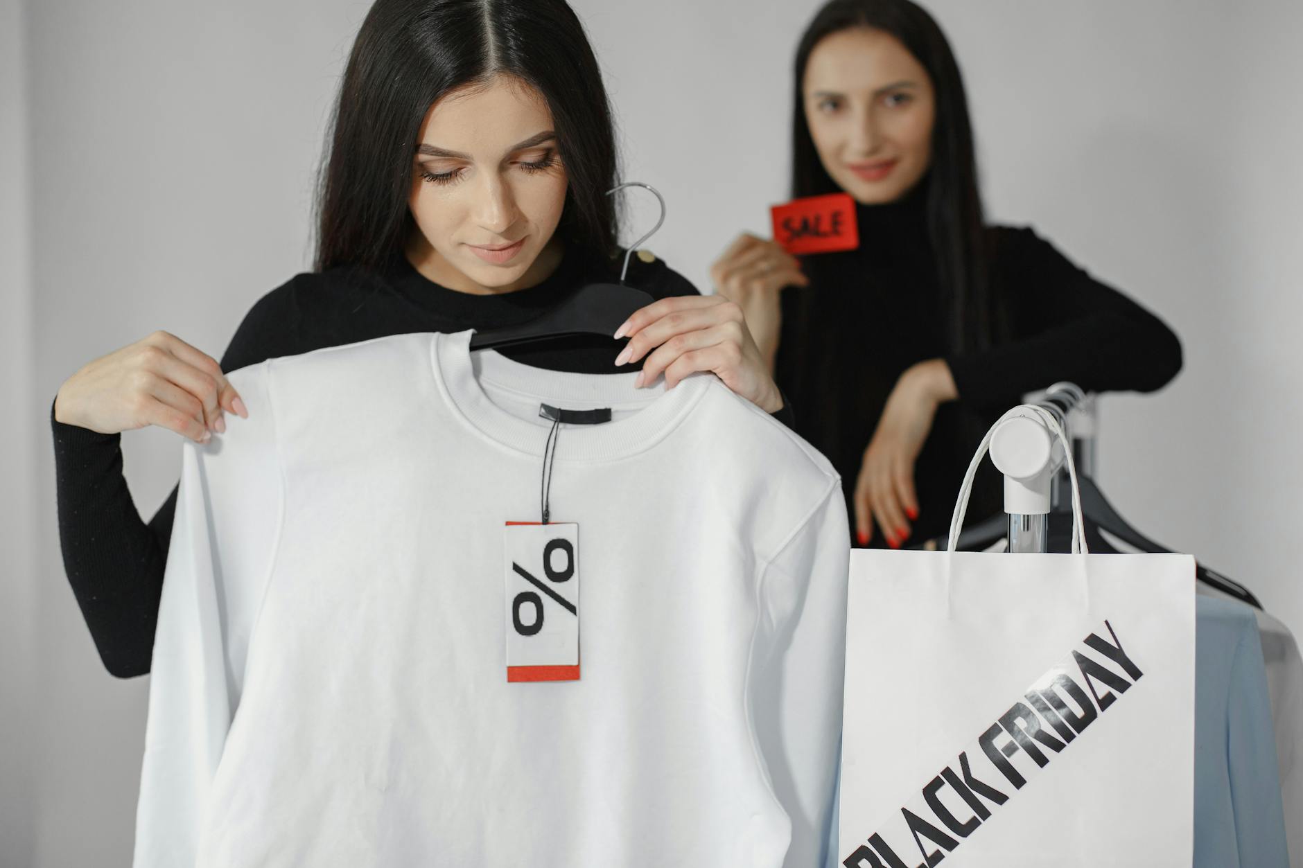 Dwie kobiety robią zakupy na wyprzedaży z dużymi rabatami na ubrania