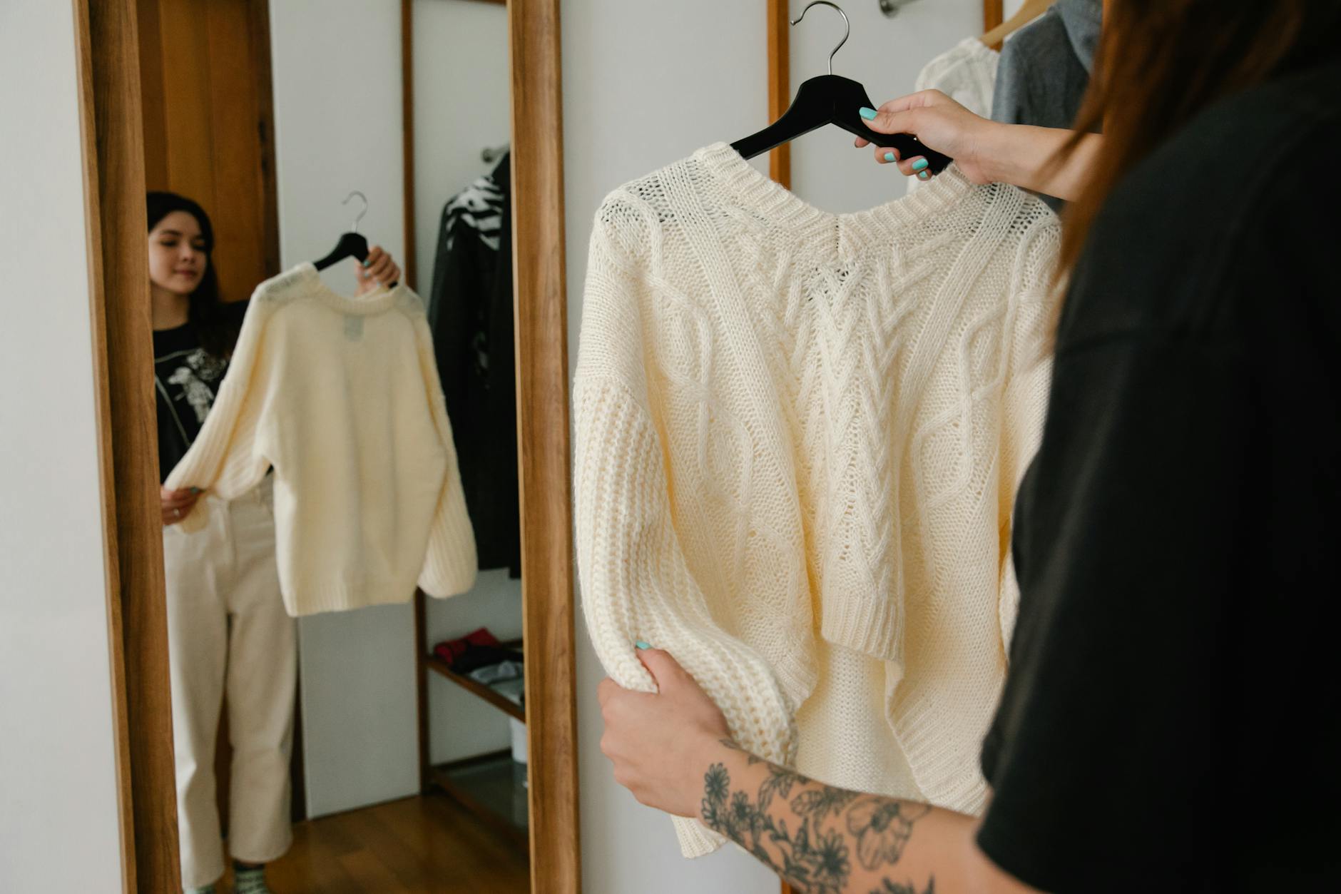 Kobieta przymierza dzianinowy sweter przed lustrem w domu
