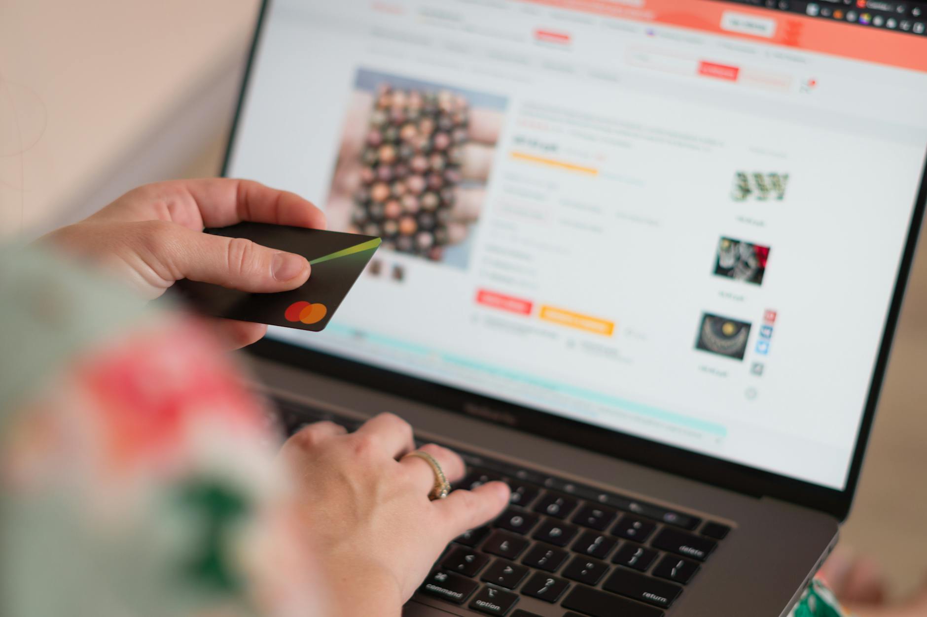 Kobieta robi zakupy online na laptopie, trzymając w ręku kartę płatniczą