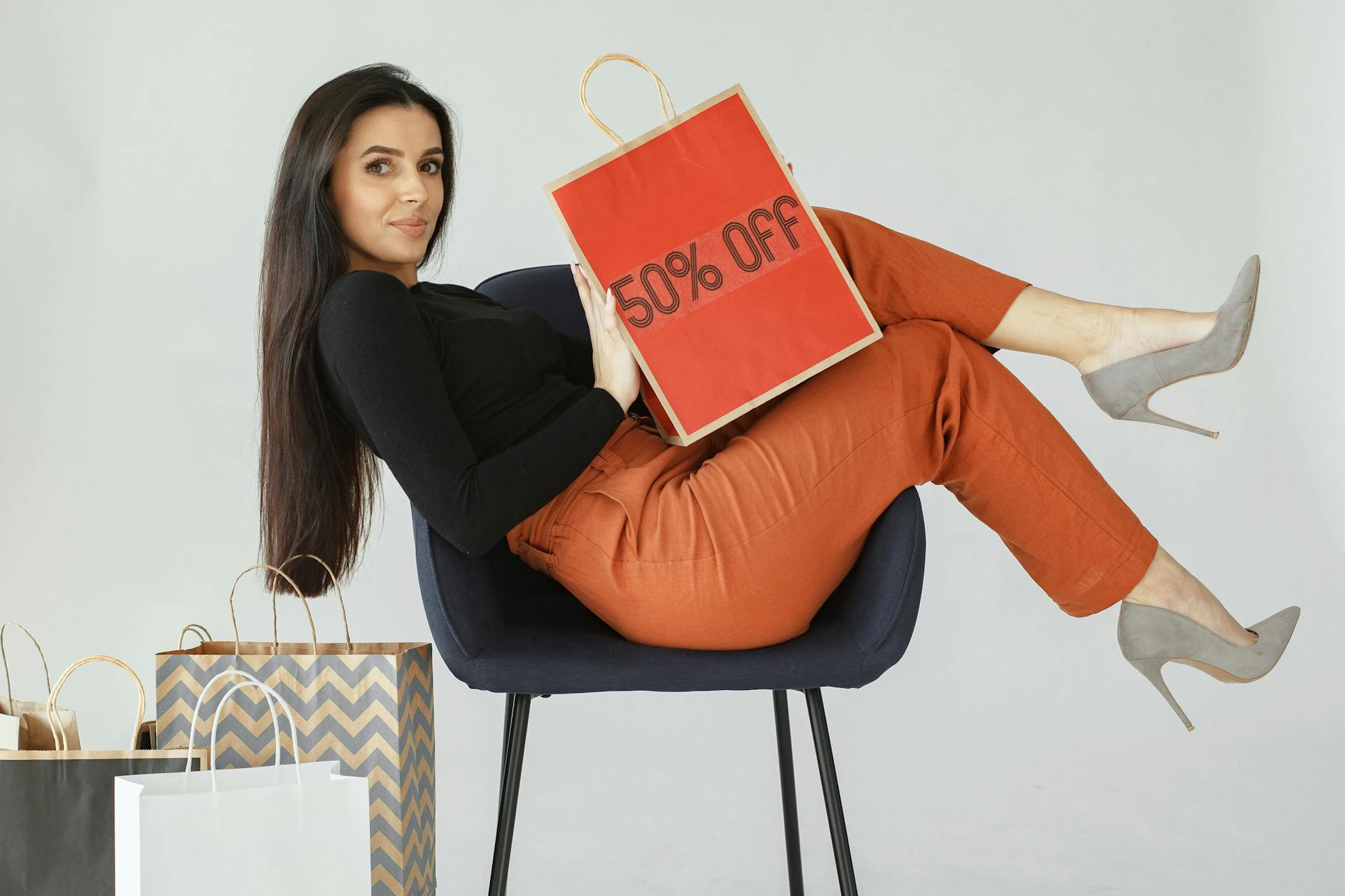 Kobieta z torbą zakupową z napisem 50% otoczona innymi torbami